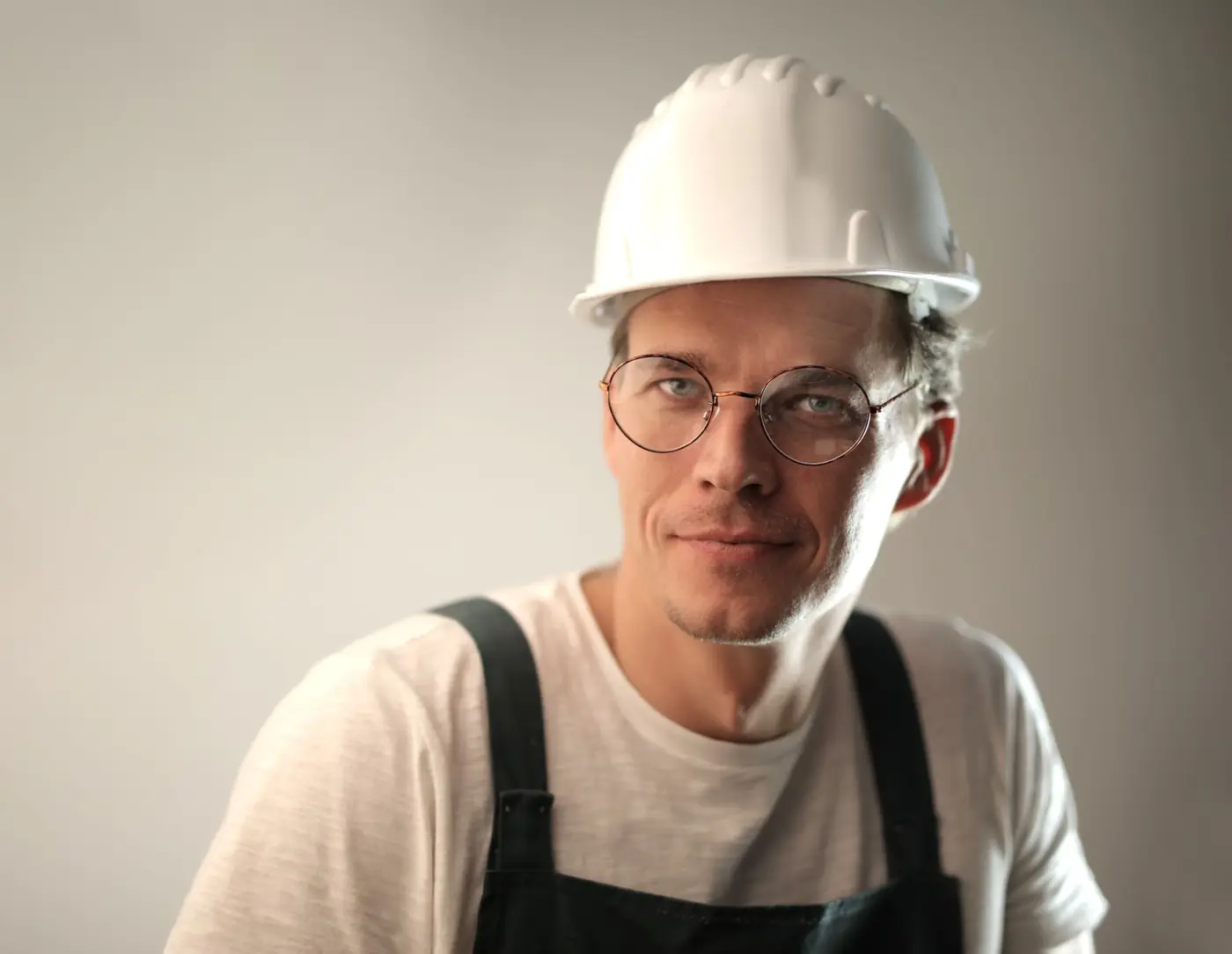 Smiling construction worker in a white hard hat and glasses